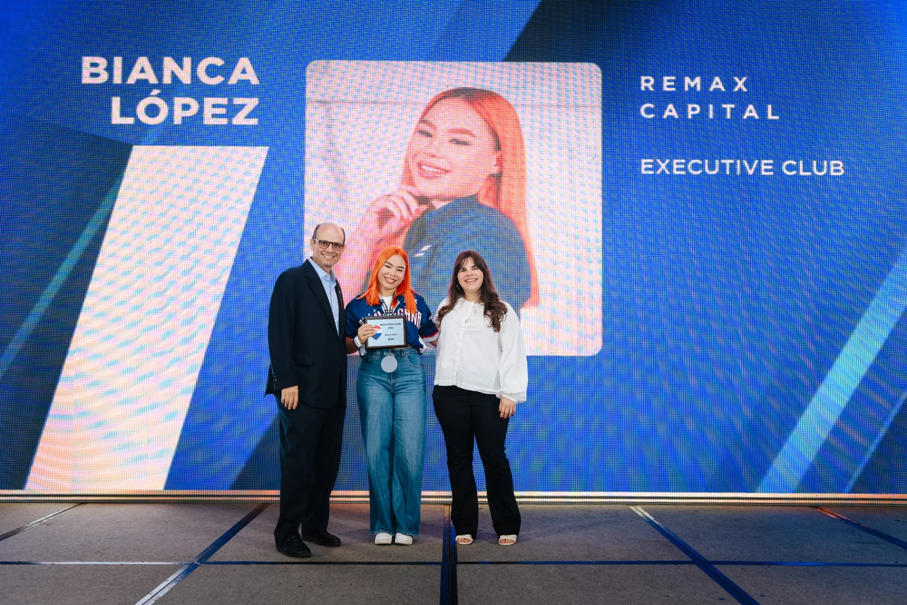 Bianca López recibiendo su reconocimiento Executive Club en un evento de RE/MAX